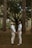 a couple of men standing next to each other in a forest