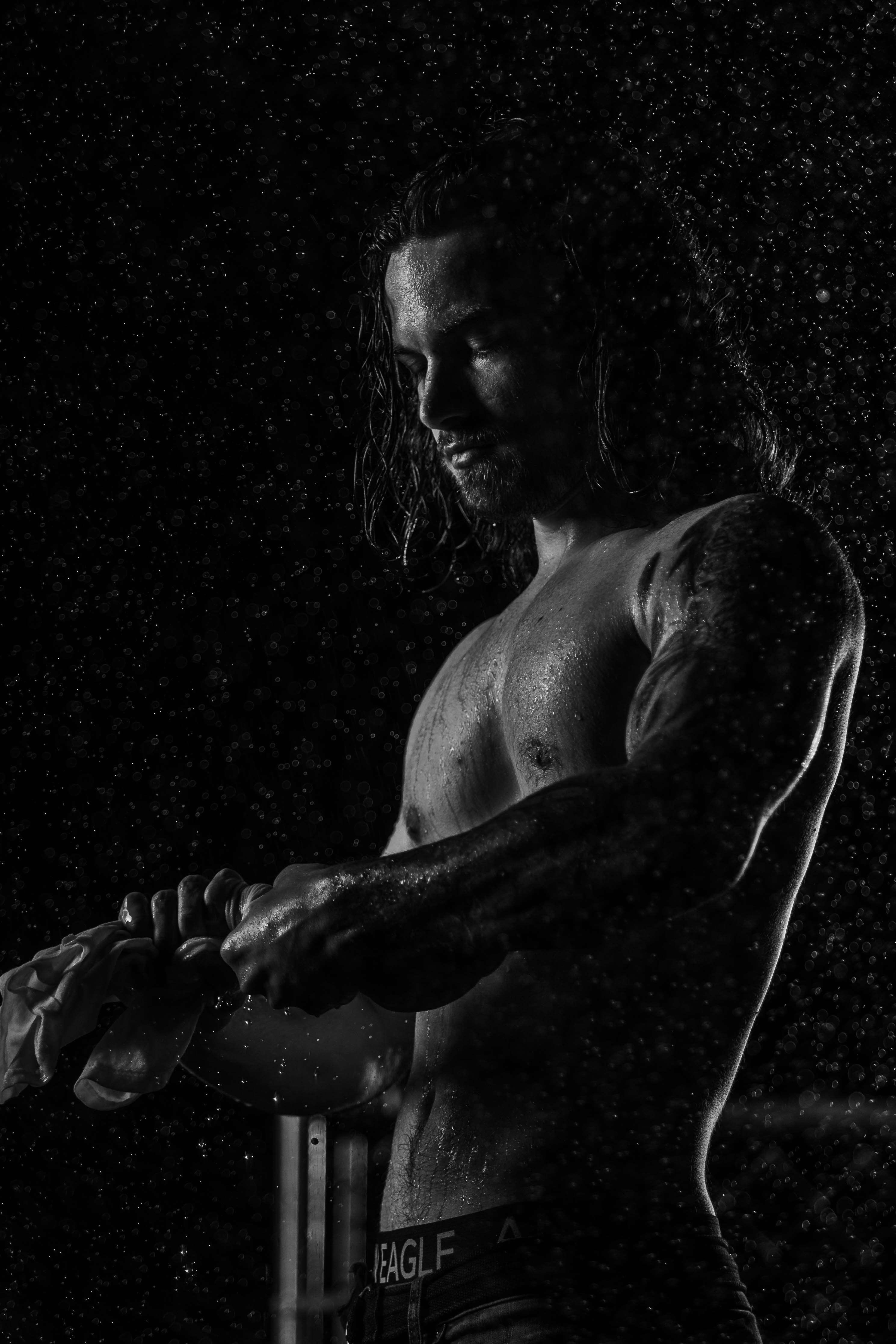 a shirtless man holding a baseball bat in the rain