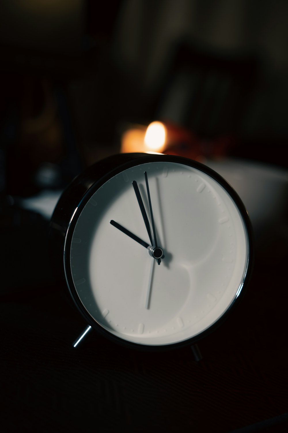 a clock sitting on top of a table next to a candle