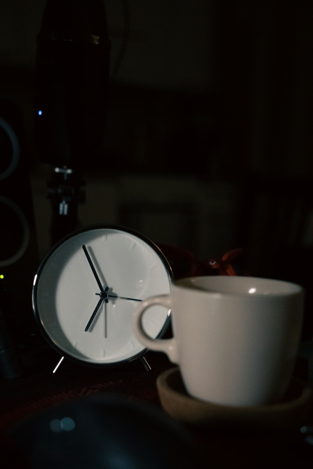 a coffee cup sitting next to a clock on a table
