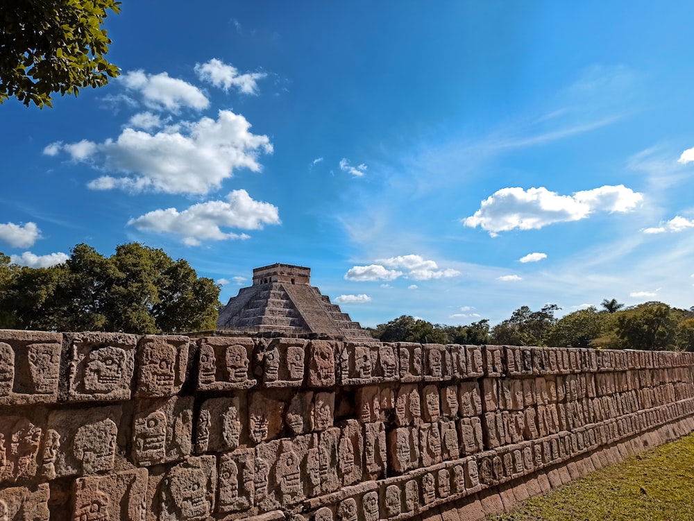 a stone wall with a pyramid in the background
