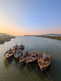 A serene river scene with fishermen in wooden boats at sunrise.