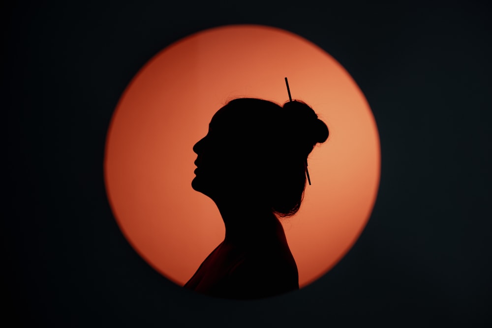 a silhouette of a woman in front of a sun