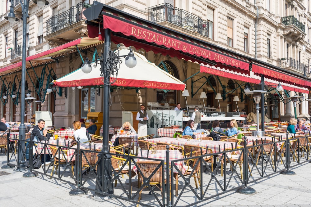 a group of people sitting at tables outside of a restaurant