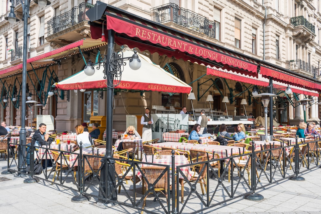 a group of people sitting at tables outside of a restaurant,