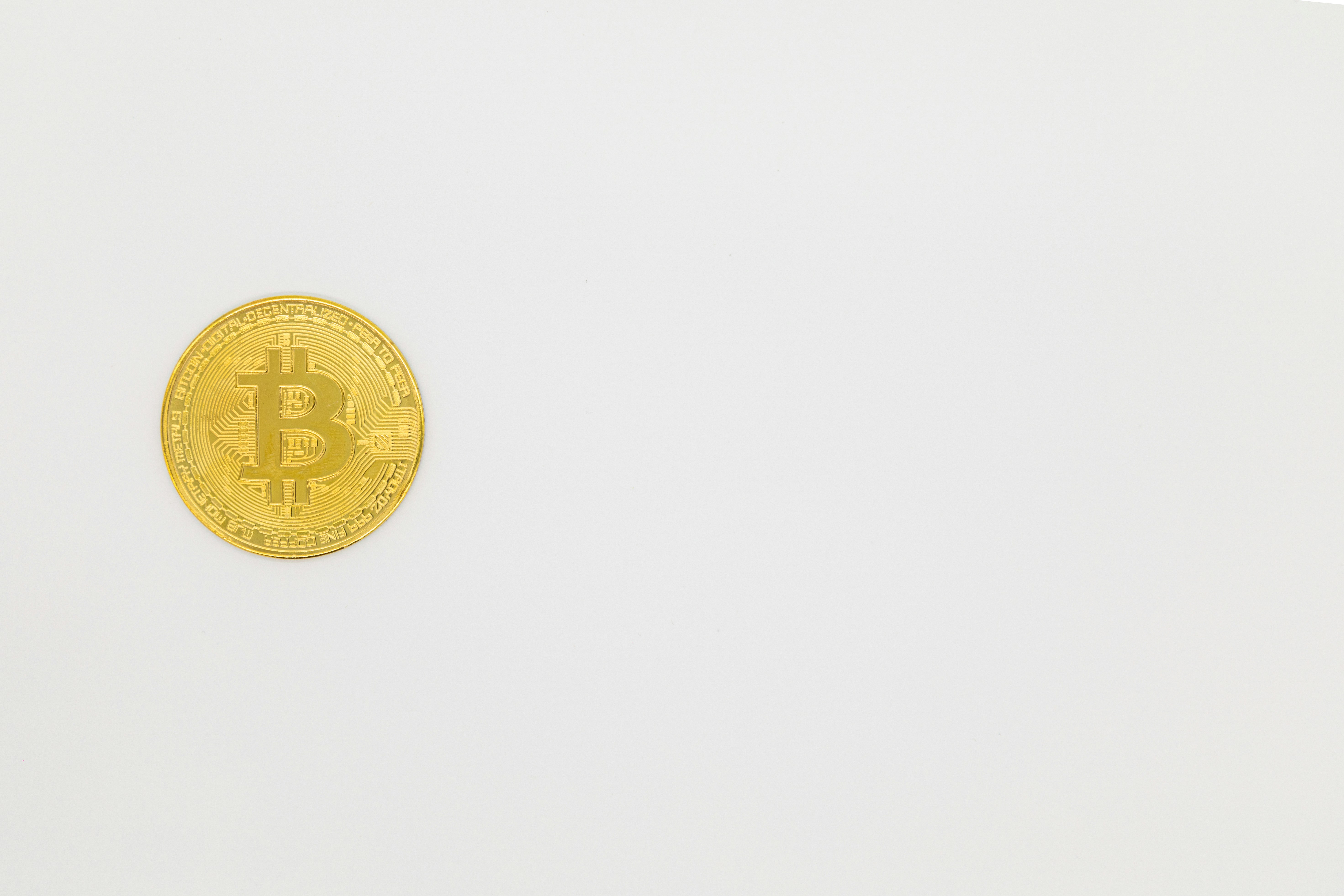 a gold bit coin sitting on top of a white surface