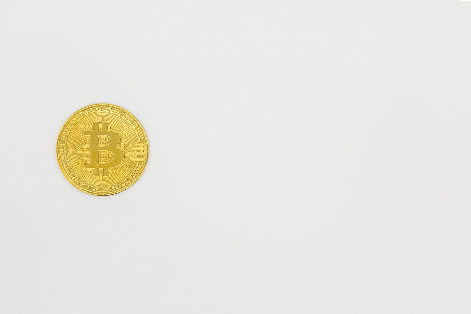 a gold bit coin sitting on top of a white surface