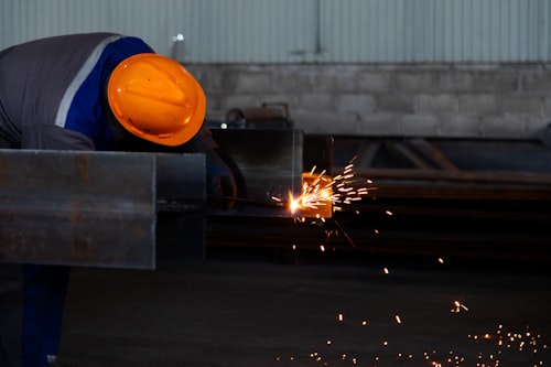 A man wearing a hard hat working on a piece of metal