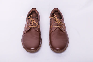 A pair of modern brown leather shoes placed on a clean white surface.