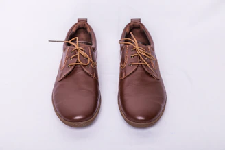 A pair of modern brown leather shoes placed on a clean white surface.