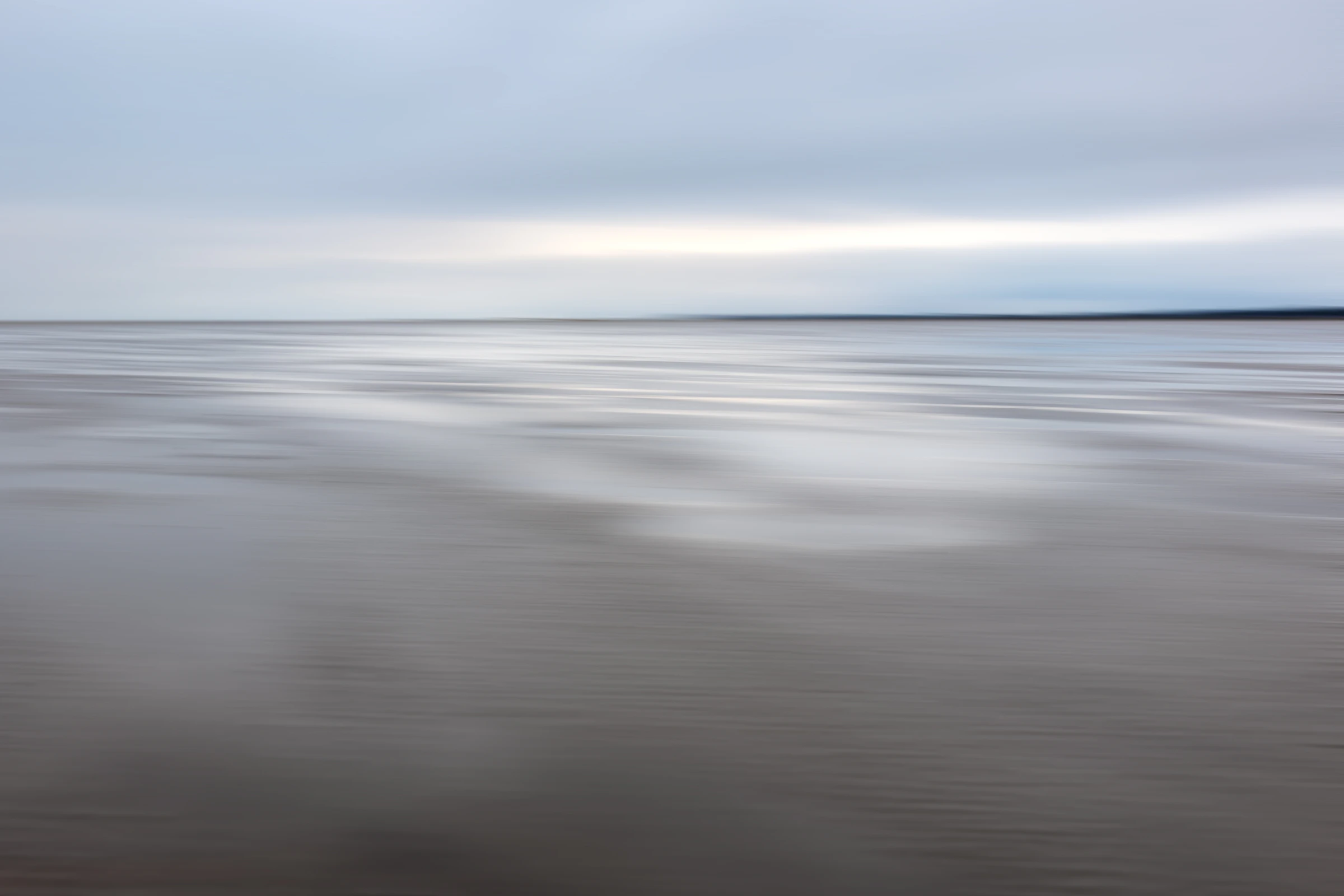 Soft silver light over wet sand and a distant horizon