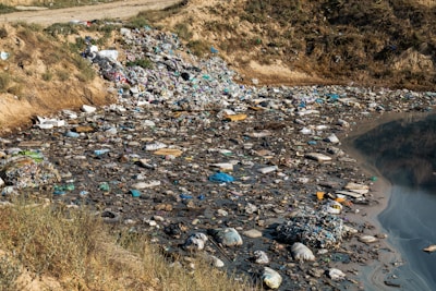a river filled with lots of trash next to a hillside