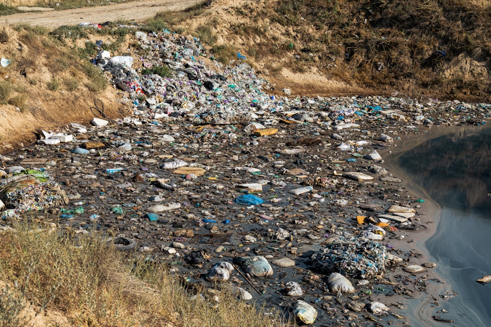 a river filled with lots of trash next to a hillside