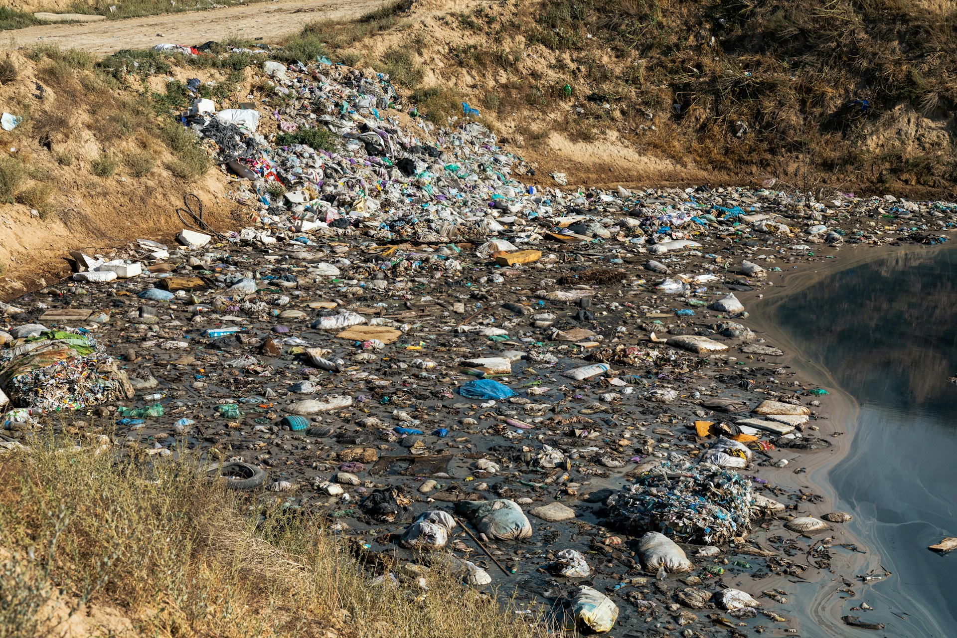 a river filled with lots of trash next to a hillside