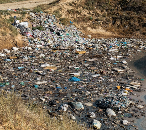a river filled with lots of trash next to a hillside