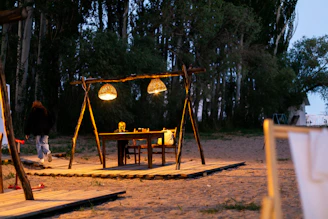 An elegant outdoor dining setup with warm lanterns and forest views at dusk.