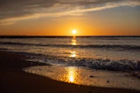 A serene beach scene at Mirissa with golden sand and gentle waves at sunset.