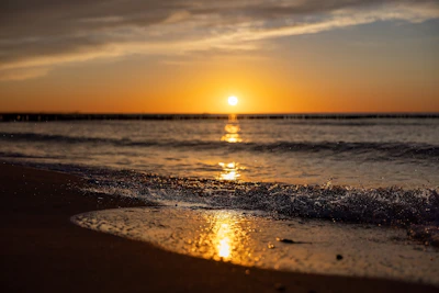 A serene beach scene at Mirissa with golden sand and gentle waves at sunset.