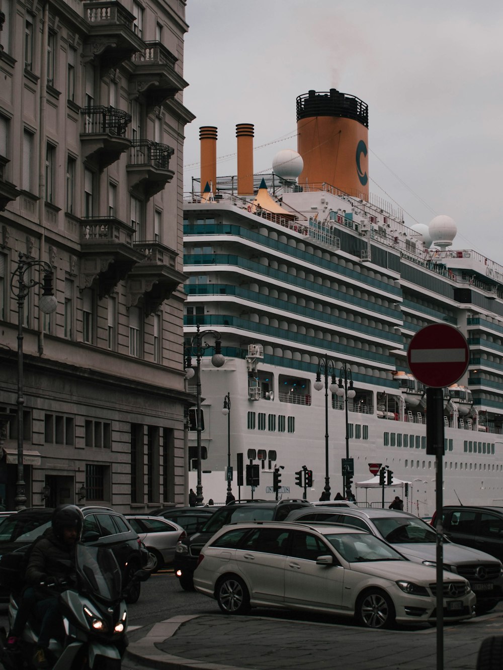 a cruise ship in the background with cars parked in front of it