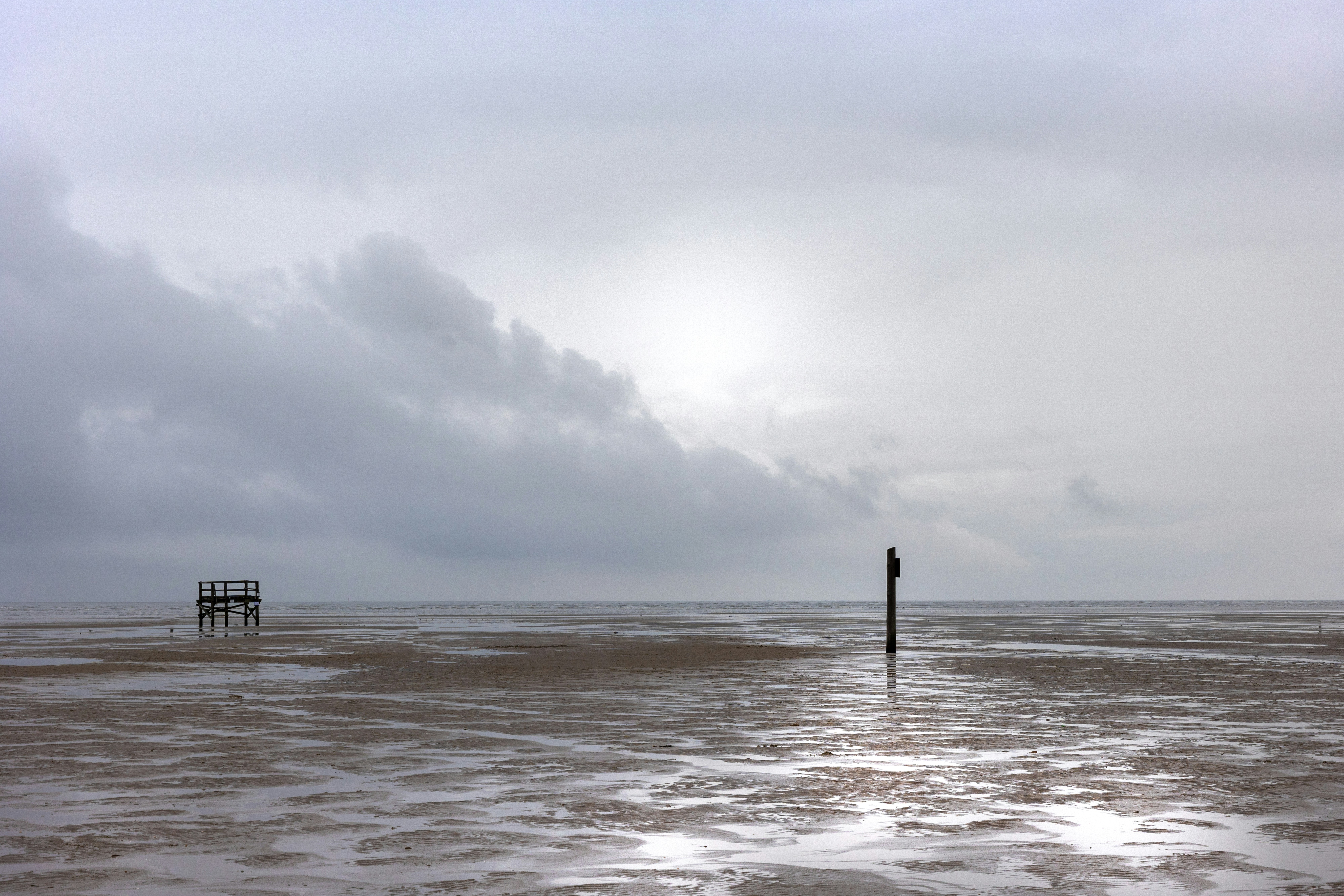 a pier sticking out of the ocean under a cloudy sky