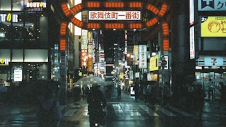 A neon-lit street in Tokyo at night, rain glistening on the pavement with blurred reflections.