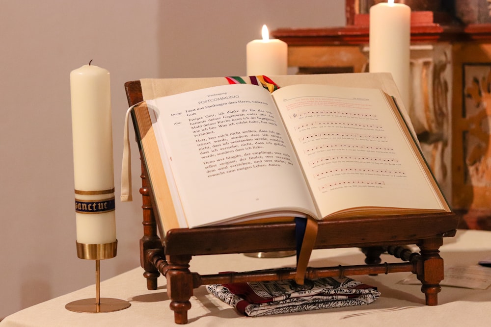 an open book sitting on top of a table next to a candle