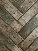 Rustic wooden-look tiles arranged in a herringbone pattern on a floor.