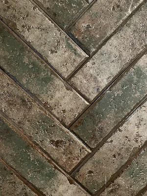 Close-up of rustic wood-look tiles laid in a herringbone pattern, showcasing warm tones and natural texture.