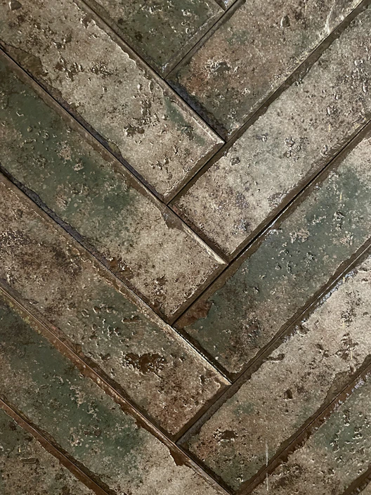 Close-up of rustic wood-look tiles laid in a herringbone pattern, showcasing warm tones and natural texture.