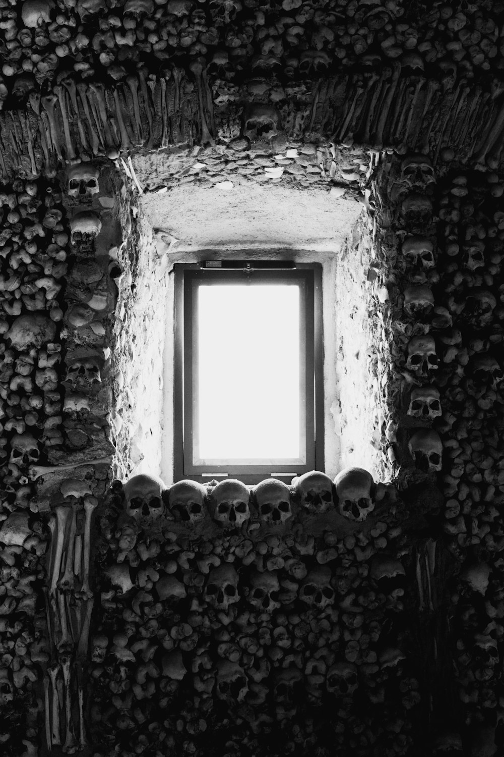 Una foto en blanco y negro de una ventana en una pared de piedra