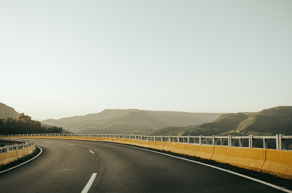 a curved road with a fence on the side of it