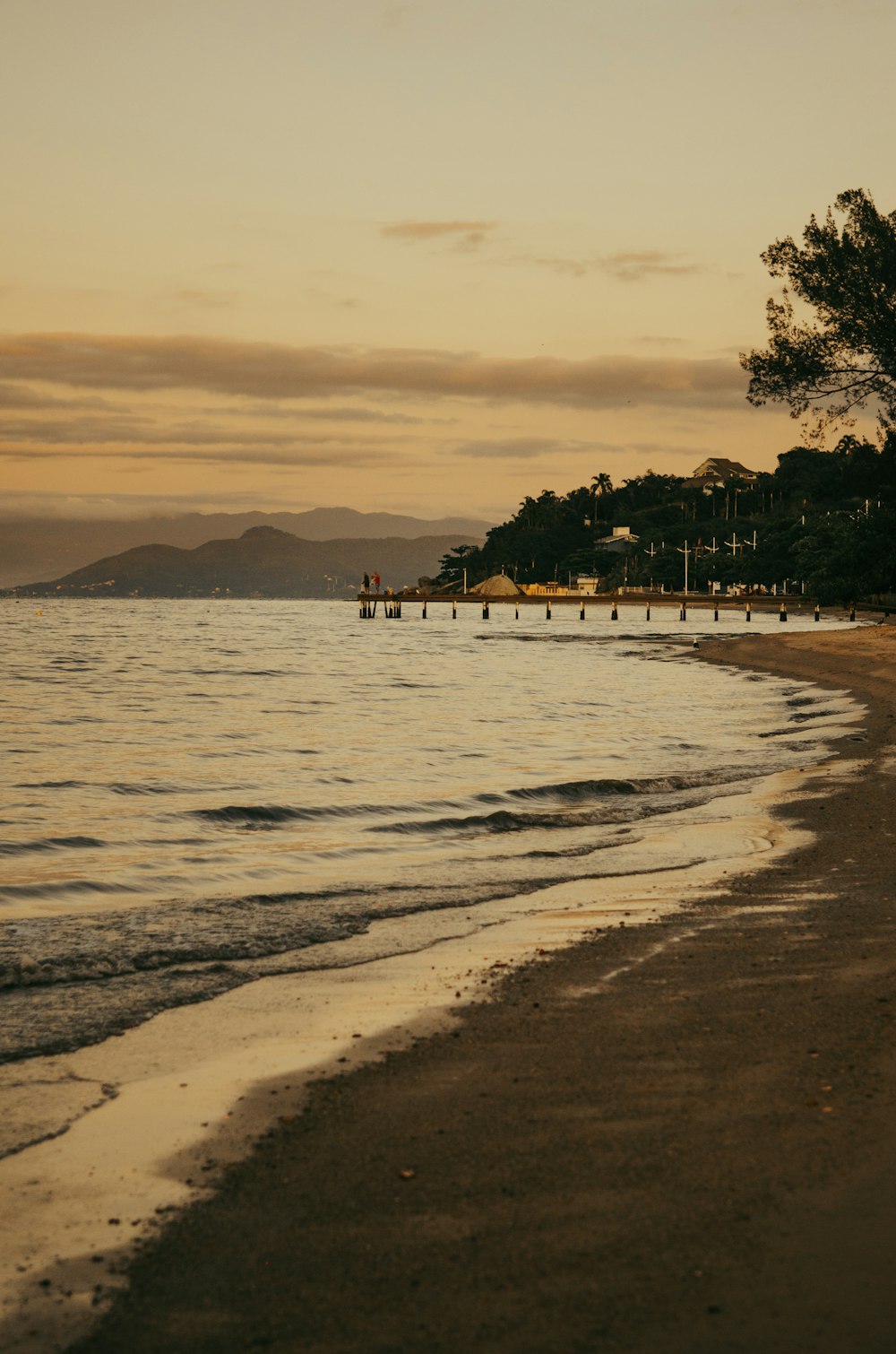 a beach at sunset with a few boats in the water