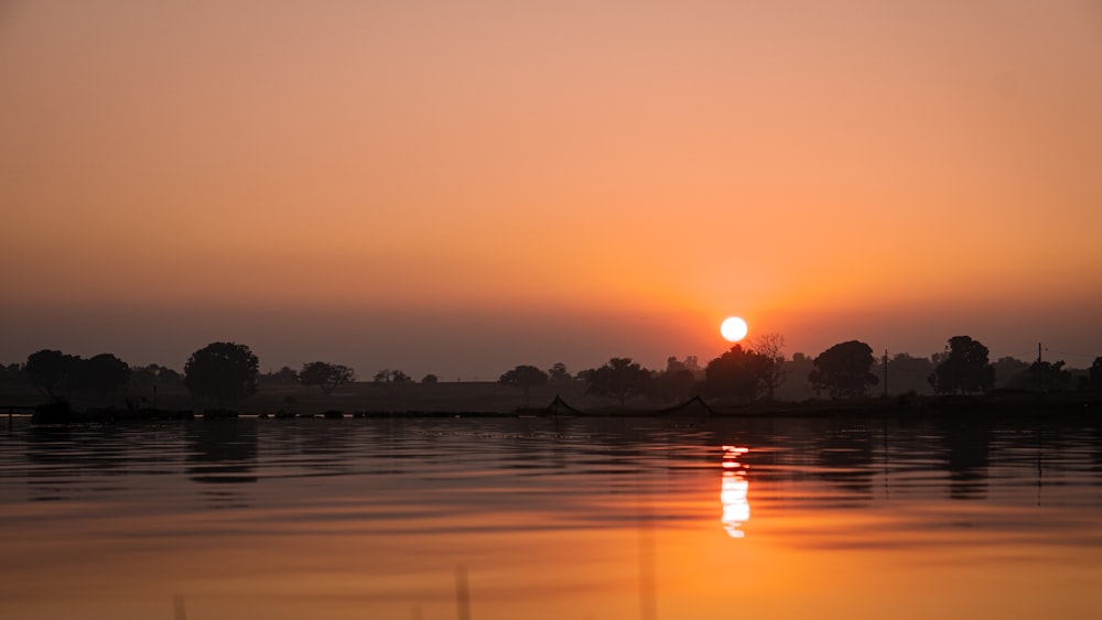 o sol está se pondo sobre um corpo de água