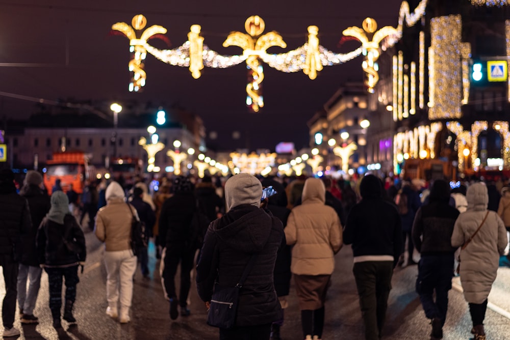 a crowd of people walking down a street at night