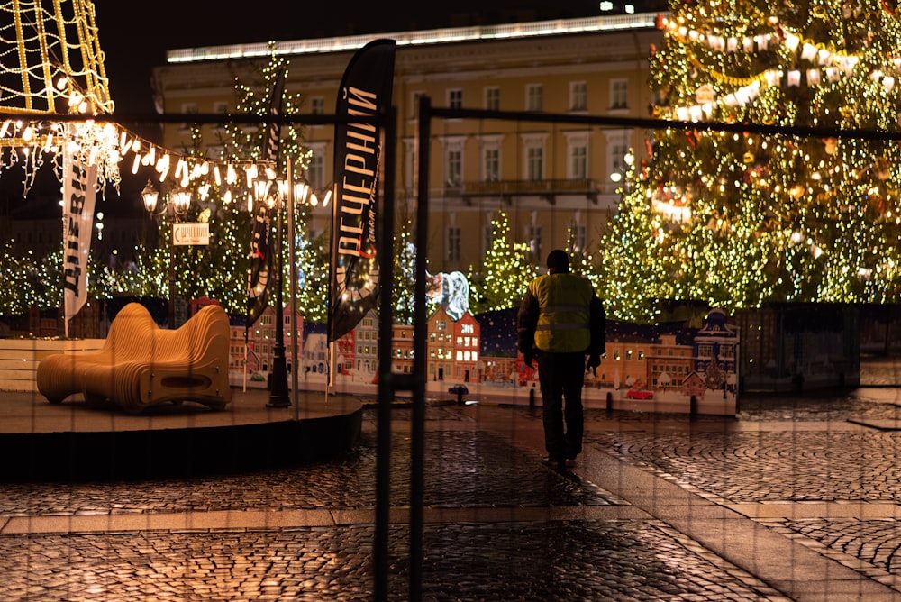 Un hombre caminando por una calle junto a un árbol de Navidad