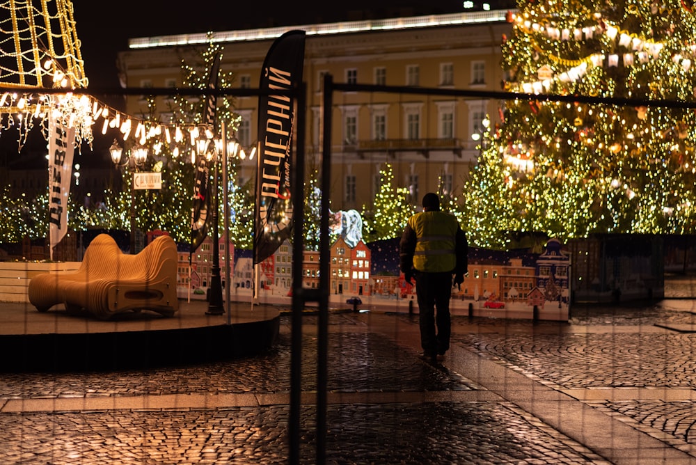 a man walking down a street next to a christmas tree