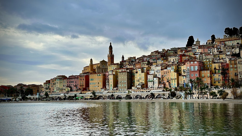 a group of buildings sitting on top of a hill next to a body of water