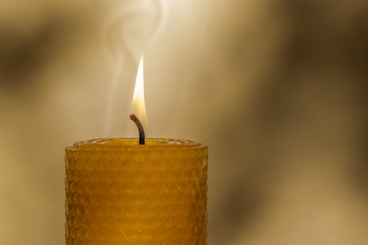 a yellow candle with a single candle stick sticking out of it