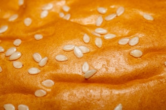 Close-up of a golden, freshly baked bagel with sesame seeds on a wooden board.