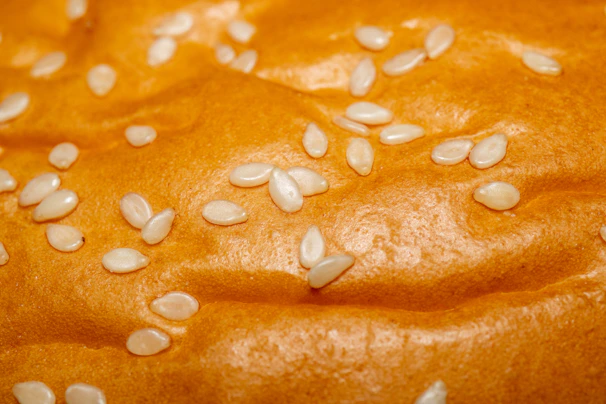Close-up of golden sesame seeds spilling from a rustic burlap sack onto a wooden surface.