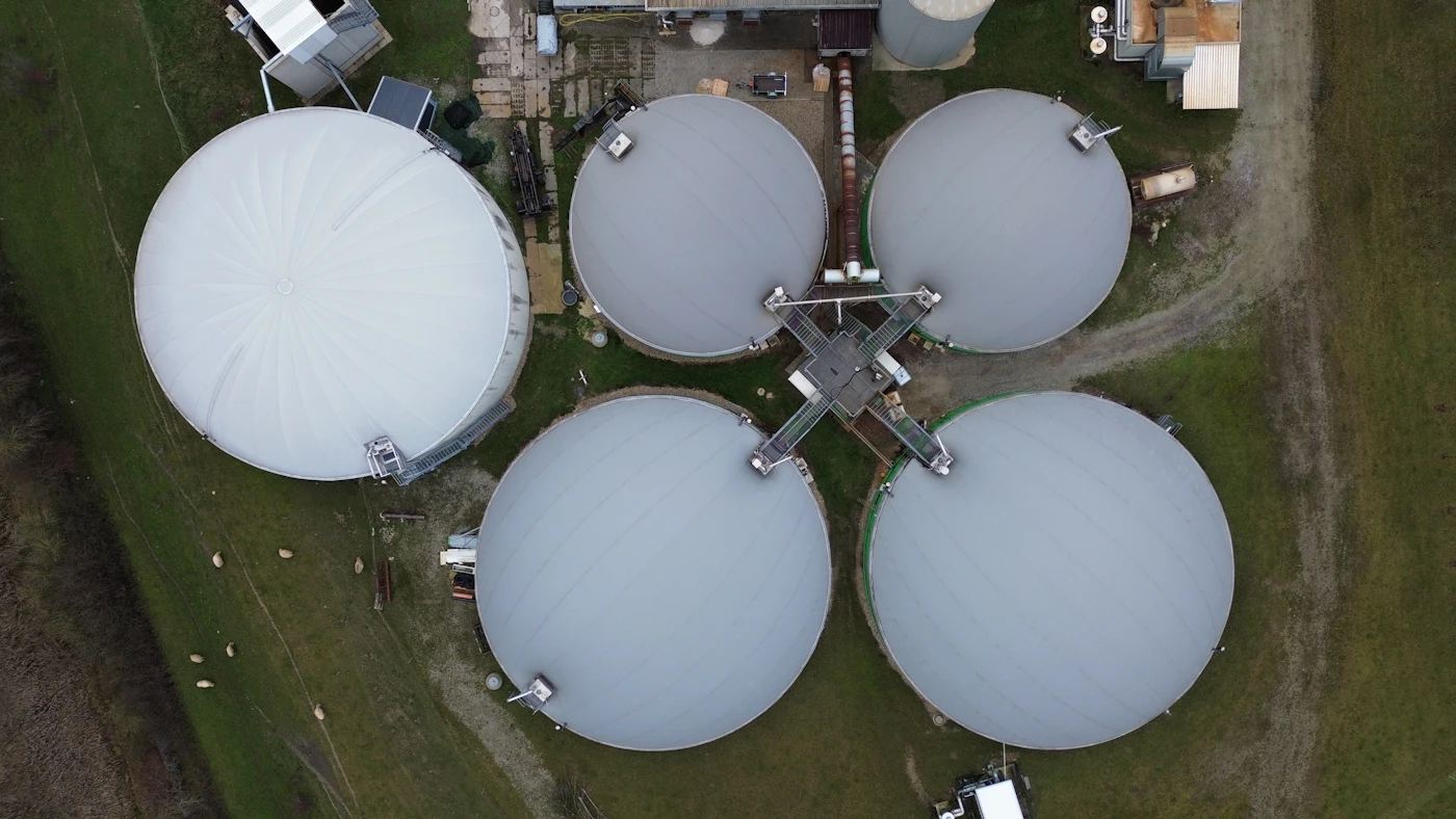 Industrial biogas storage tanks on a green field, representing a CBG / bio-energy plant