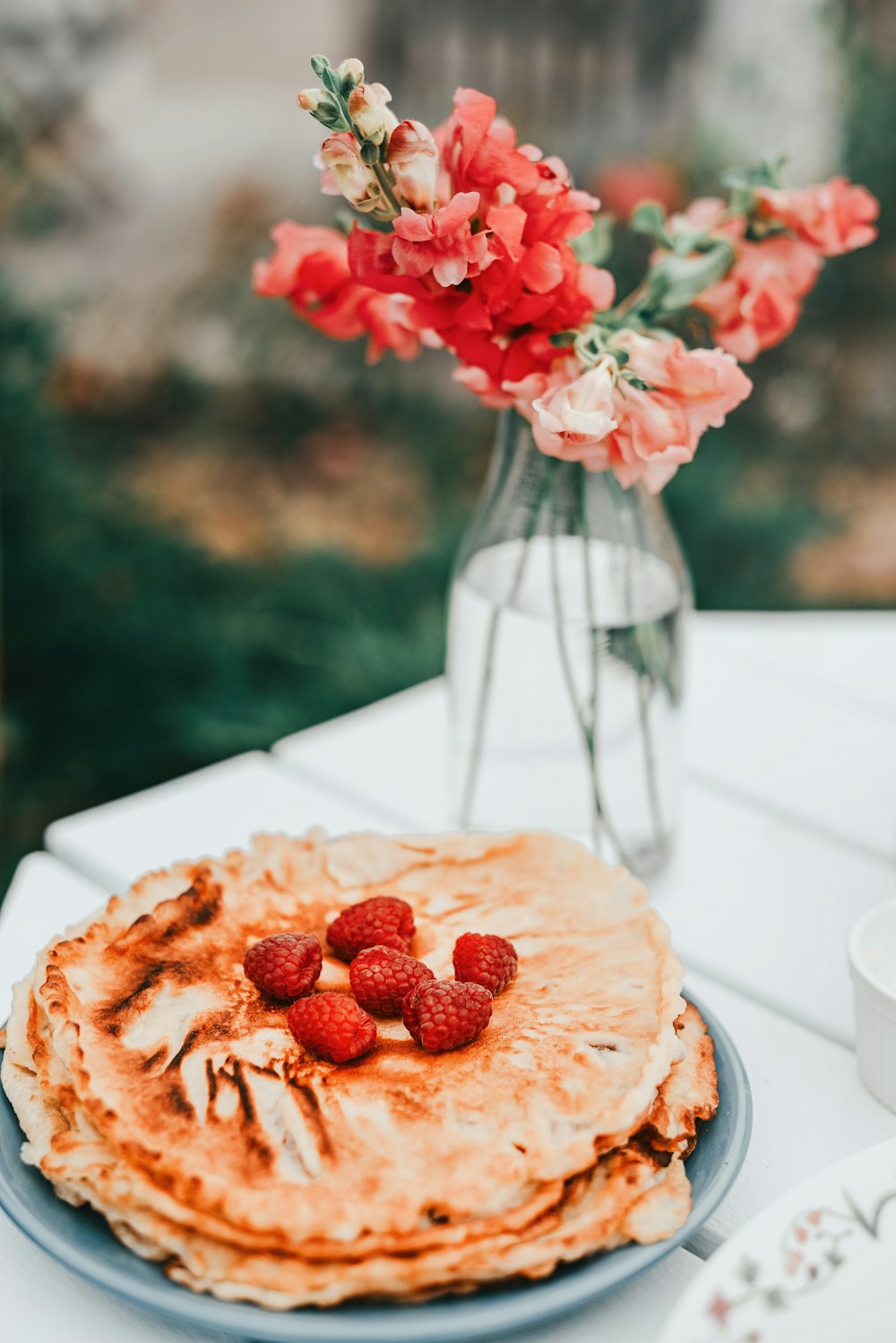 a plate of pancakes with raspberries on top of it