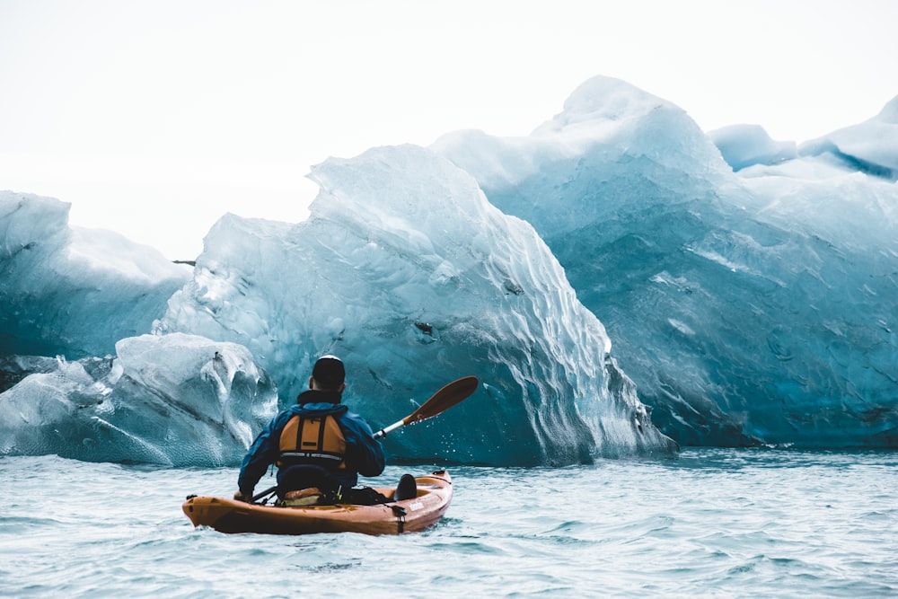 a man in a kayak in front of icebergs