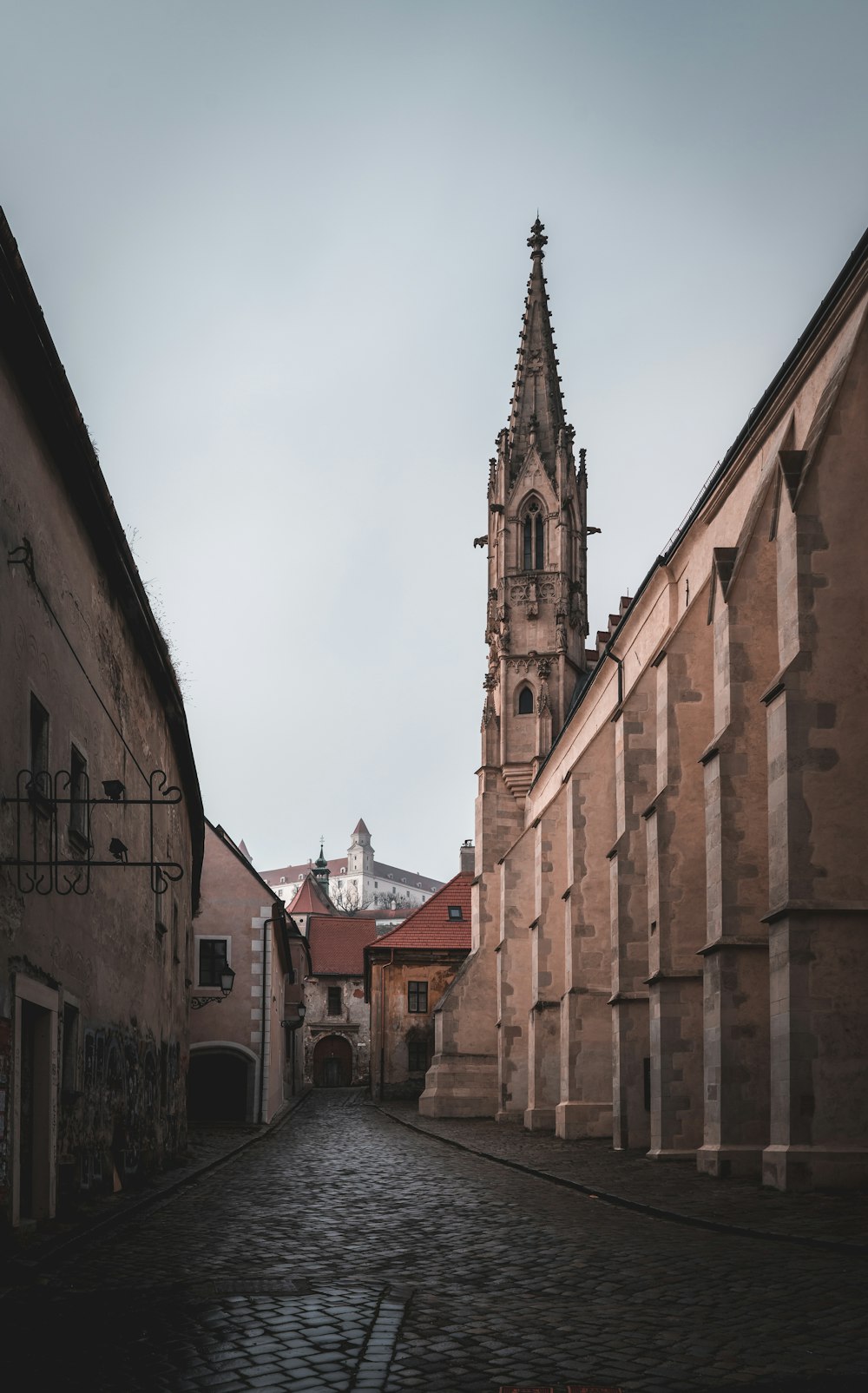 a narrow street with a church steeple in the background
