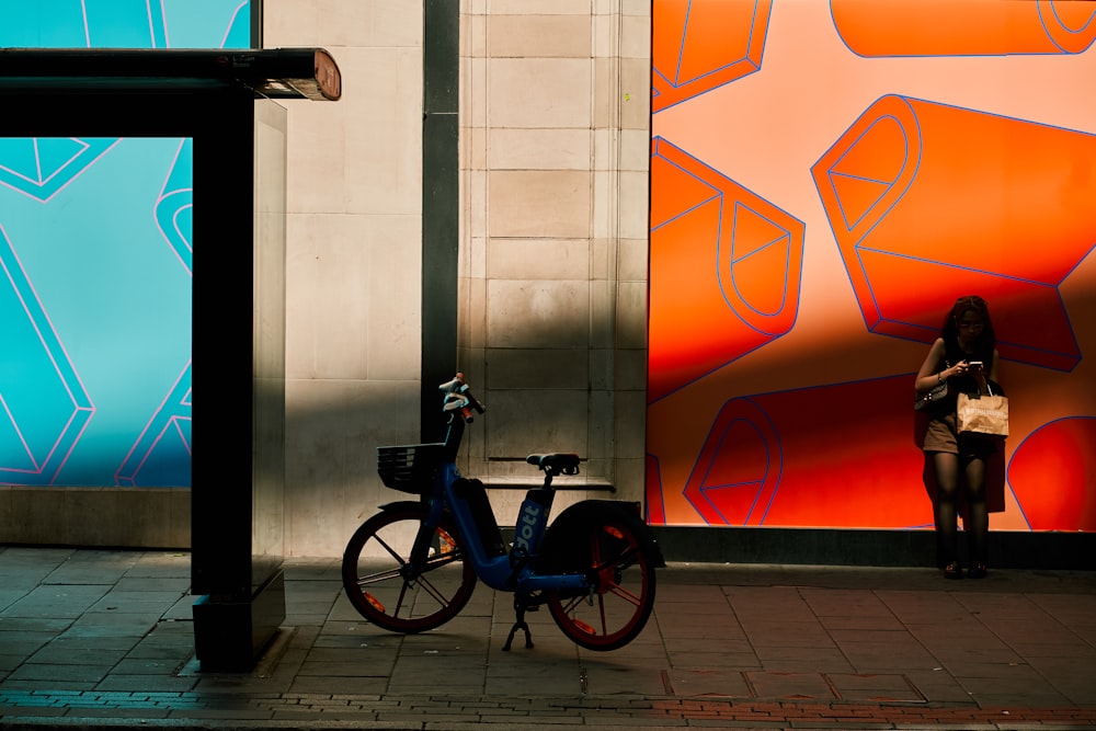 a woman standing next to a blue bike