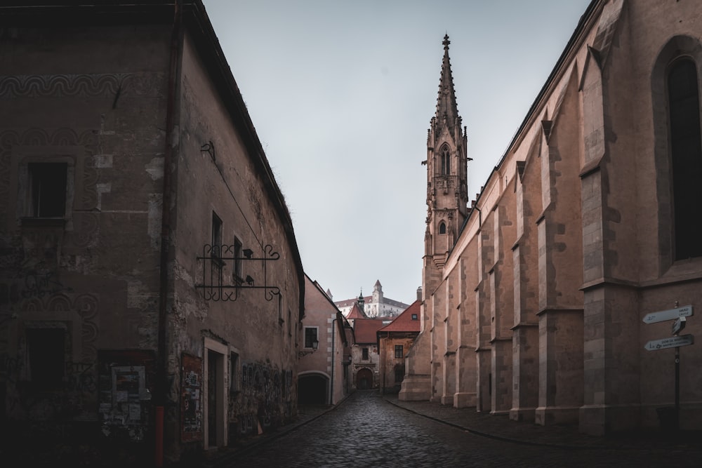 a narrow street with a church steeple in the background