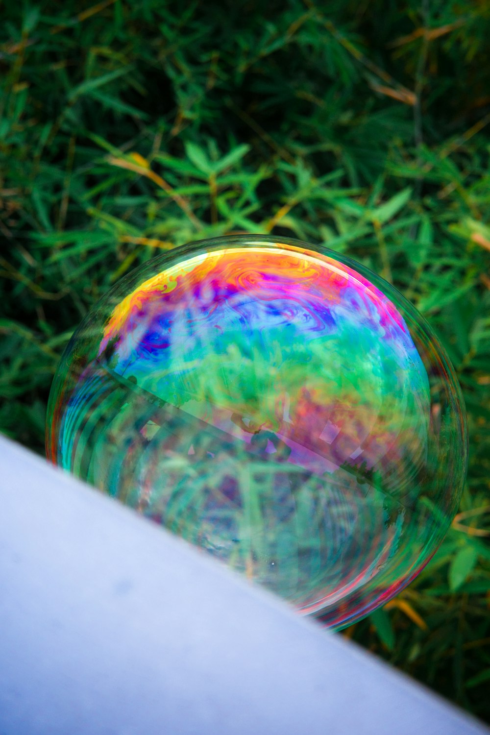 a soap bubble floating in front of a lush green field