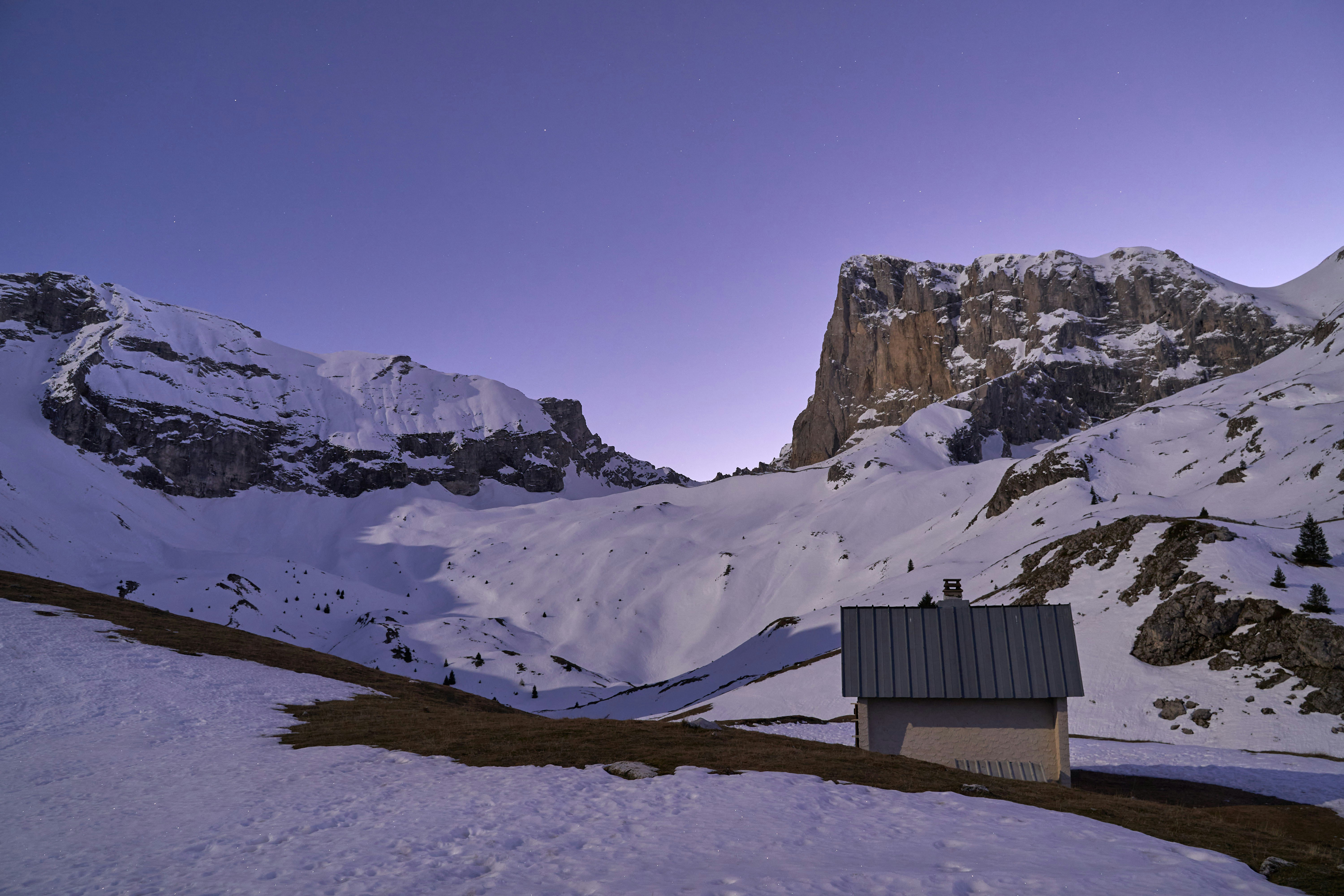 Une petite maison au milieu d’une montagne enneigée