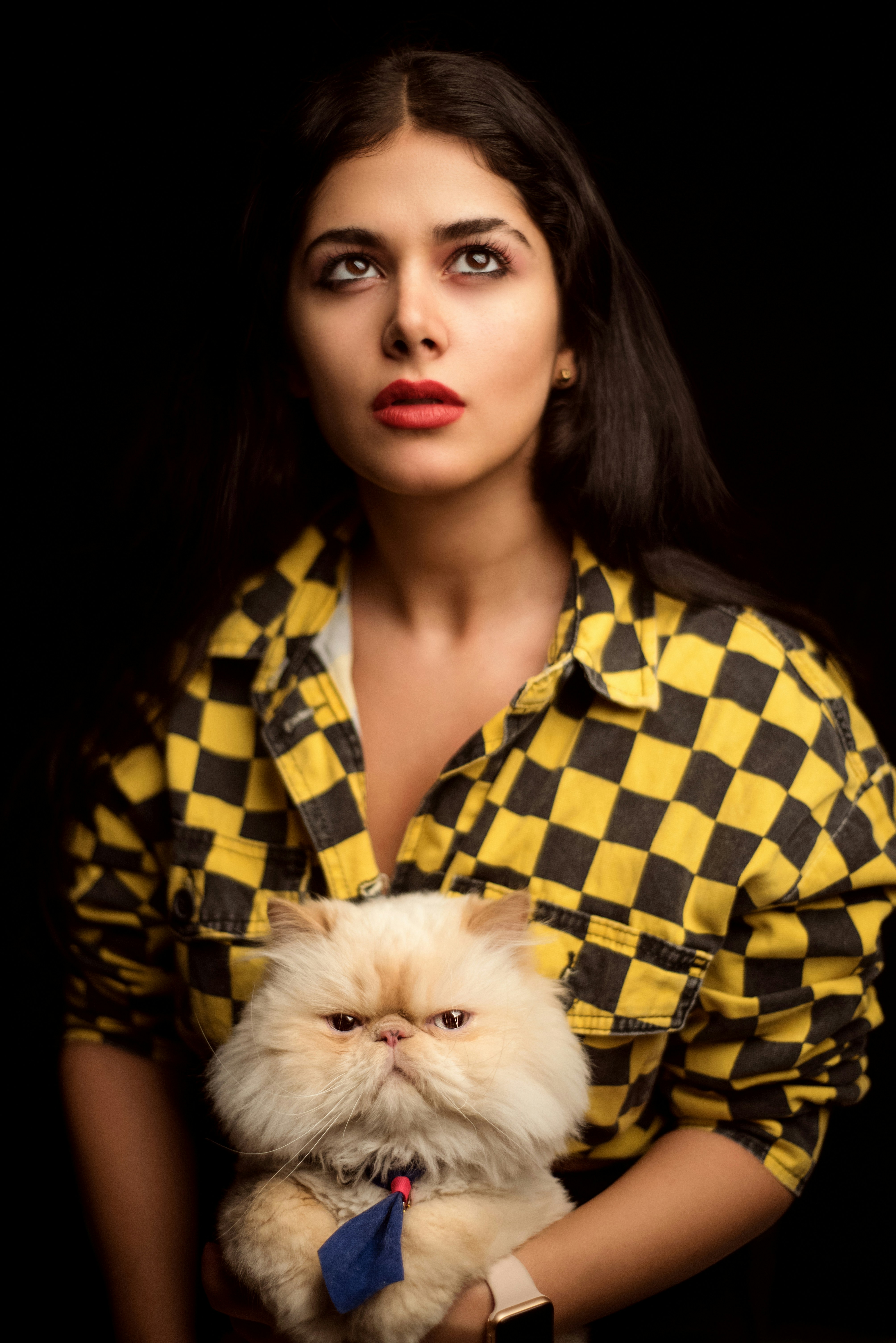 a woman in a yellow shirt holding a cat