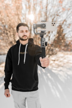 Close-up of a trendy young Asian man filming a creative video with a smartphone outdoors